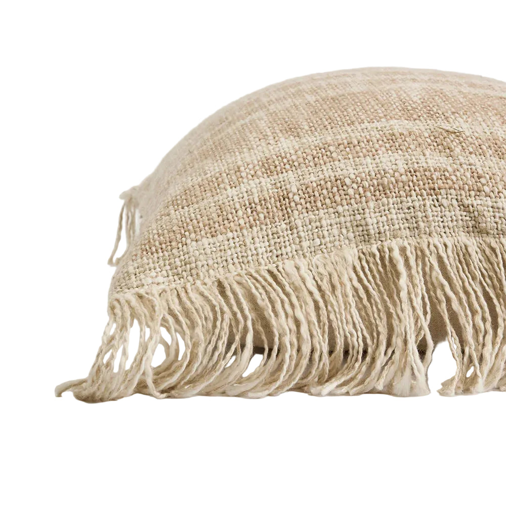 Textured beige pillow with fringes on a light background