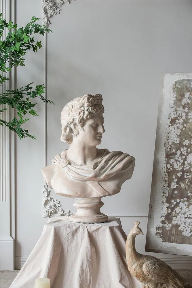 Statue of a classical bust on a pedestal with decorative elements in the background