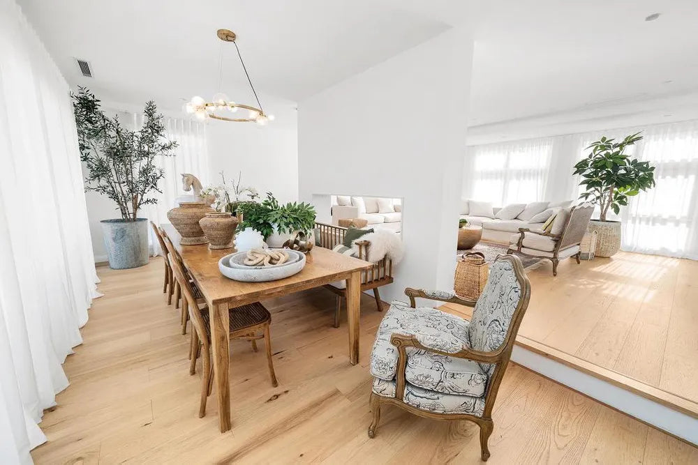 Modern living room with wooden dining table and chairs, and a sofa in the background.