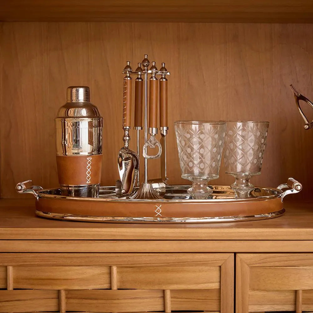 Bartender set with shaker, glasses, and tools on a wooden tray against a wooden background