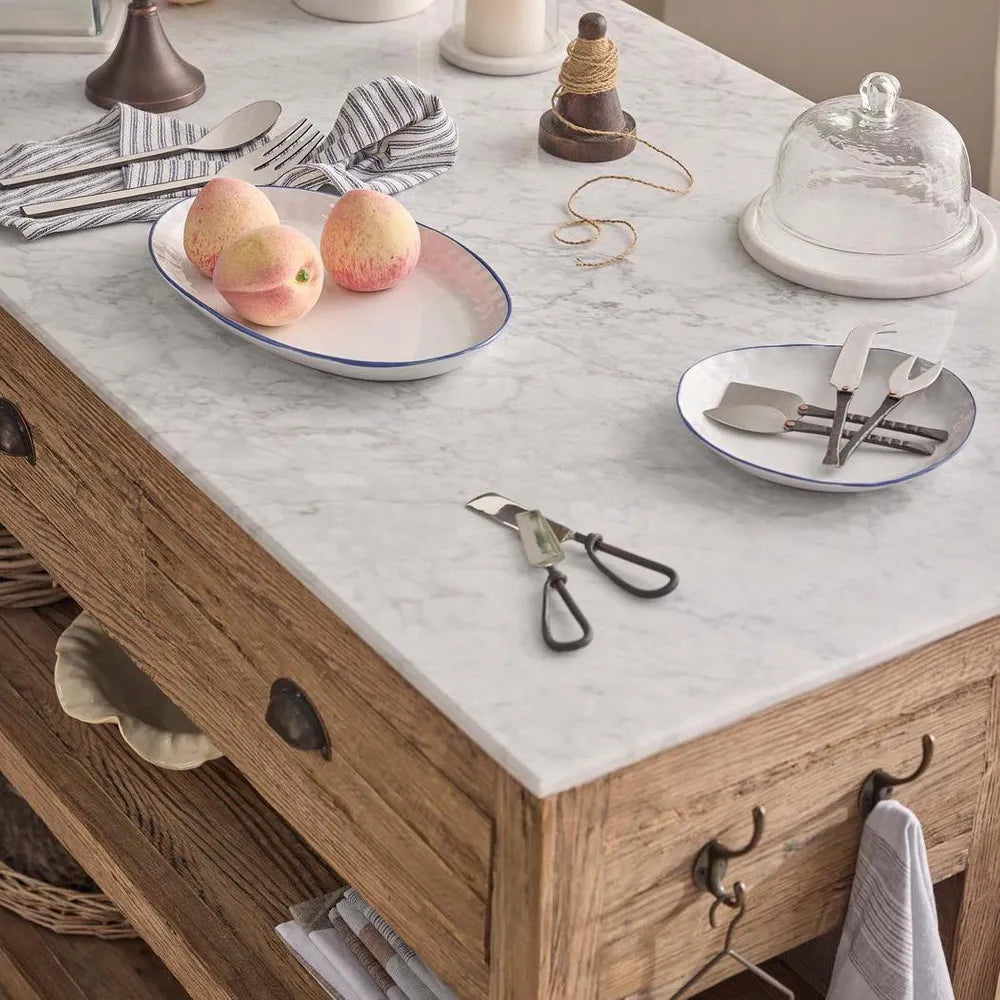 Wooden kitchen island with marble countertop, peaches, and kitchen utensils.