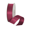 Spool of pink satin ribbon on a white background
