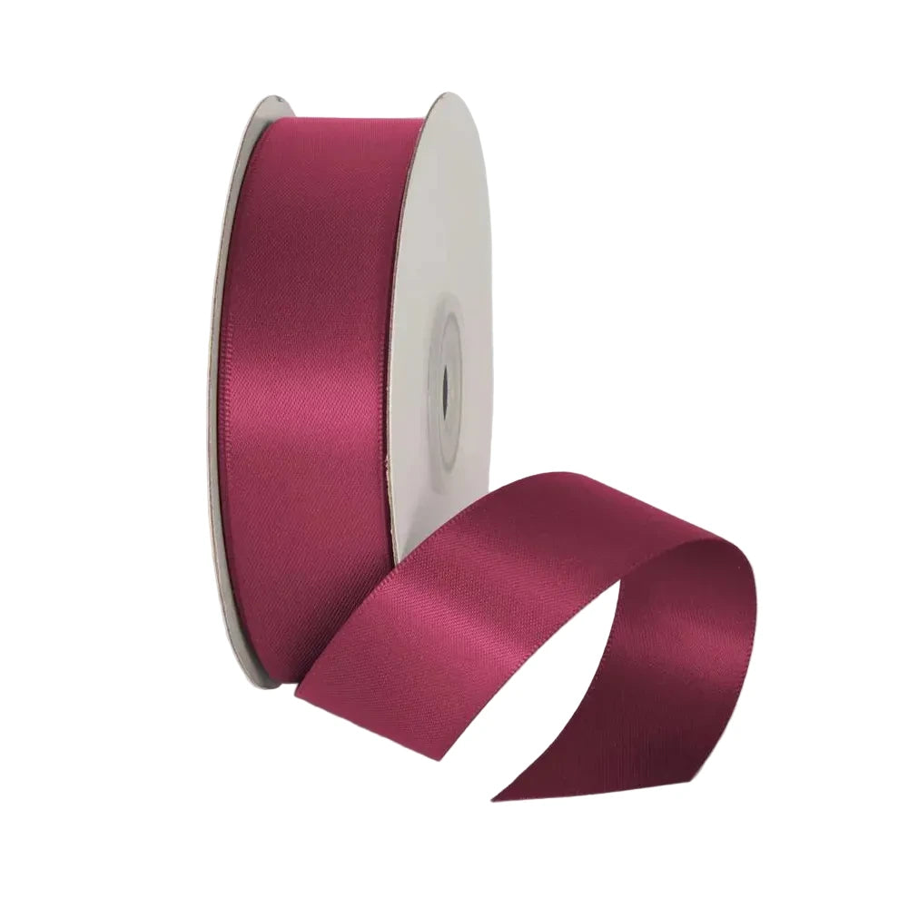 Spool of pink satin ribbon on a white background
