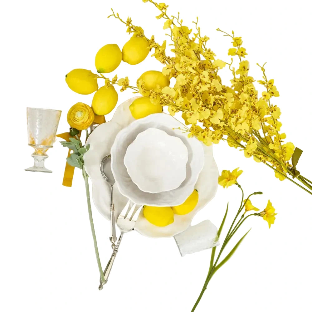 Yellow lemons and flowers on a white table setting with cutlery