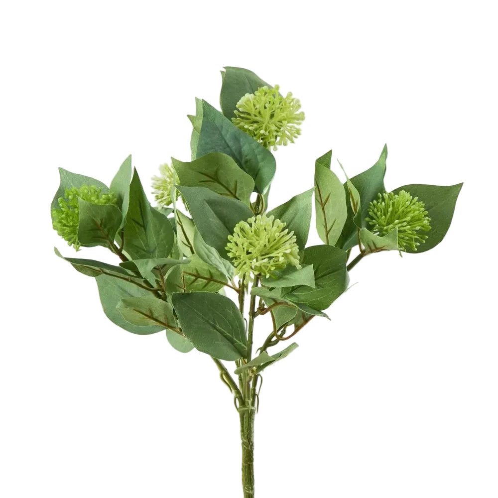 Artificial green leafy branch with small green flowers on a light gray background