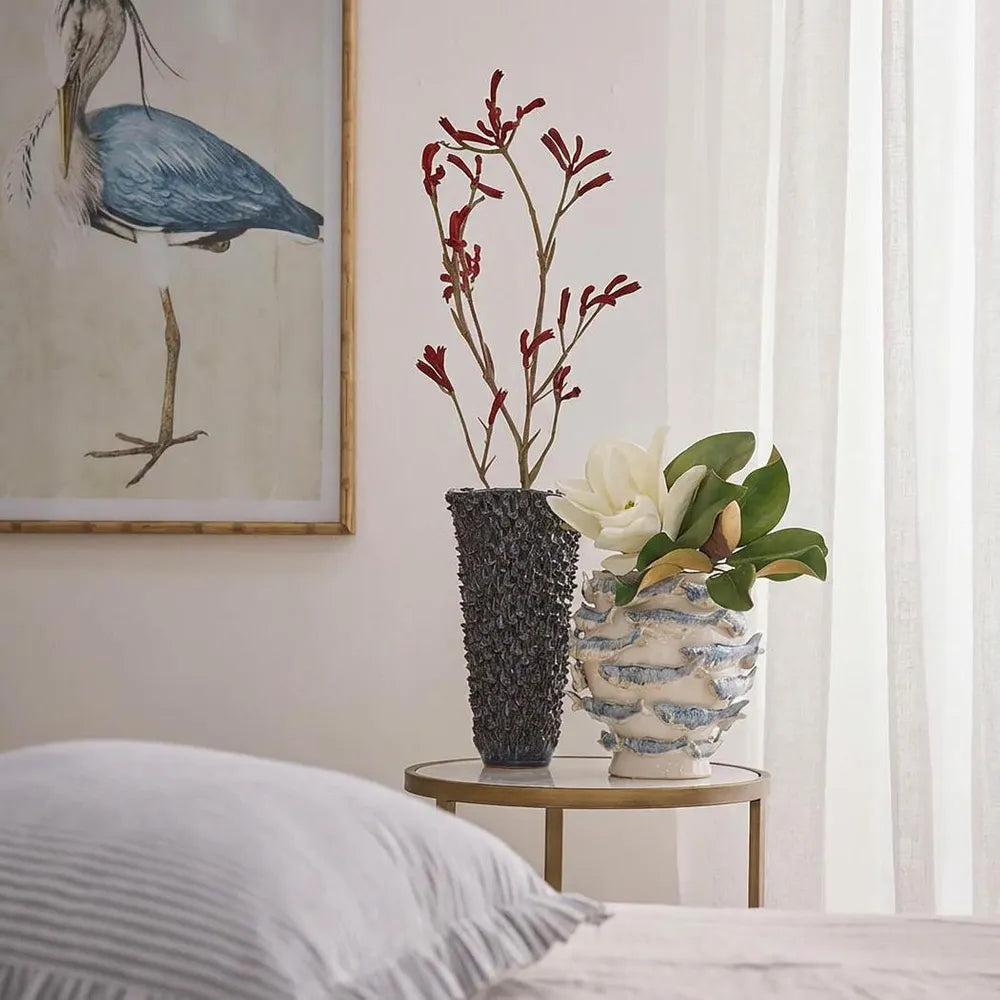 Decorative vases on a side table with a bird painting in the background