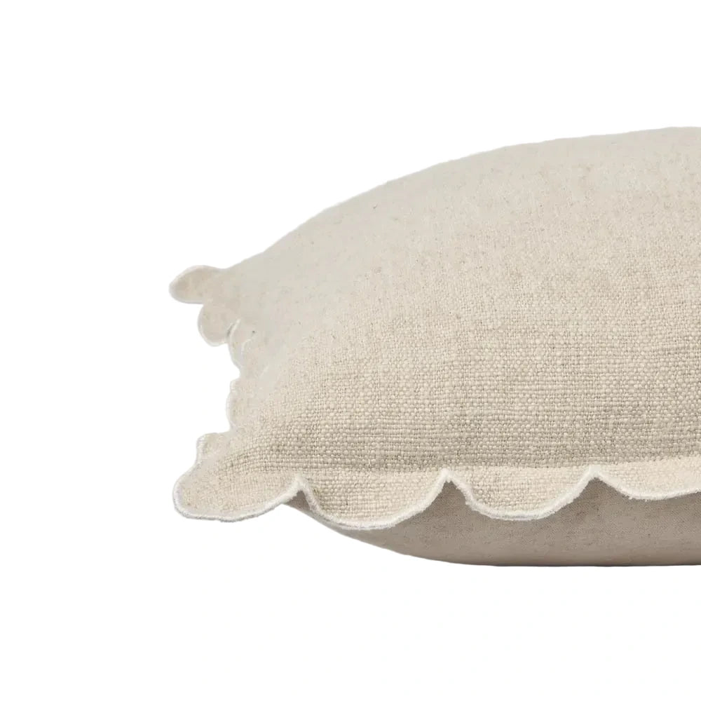 Beige pillow with scalloped edge on a light gray background