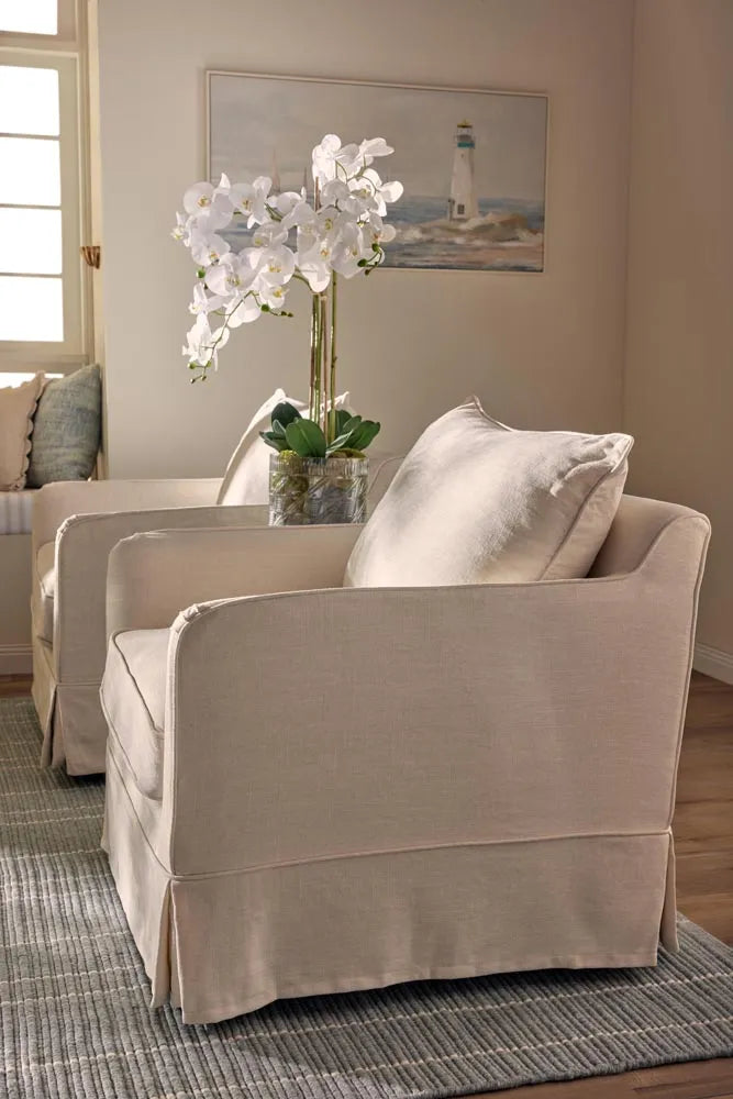 Beige armchair with a vase of white flowers on a coffee table in a living room.