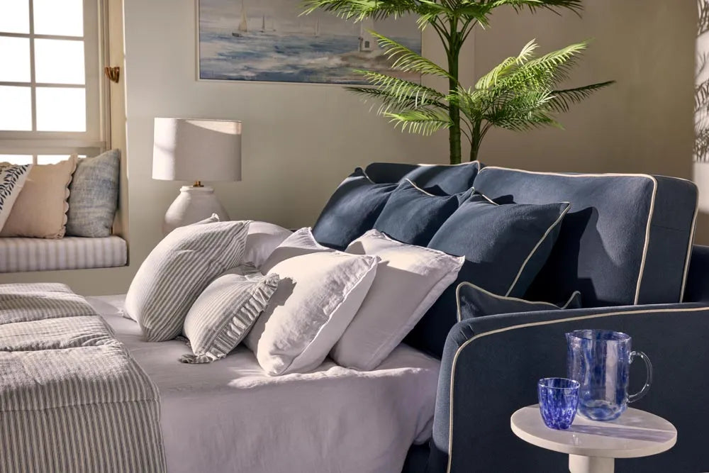 Cozy living room with a blue sofa, gray cushions, and a small table with a cup.