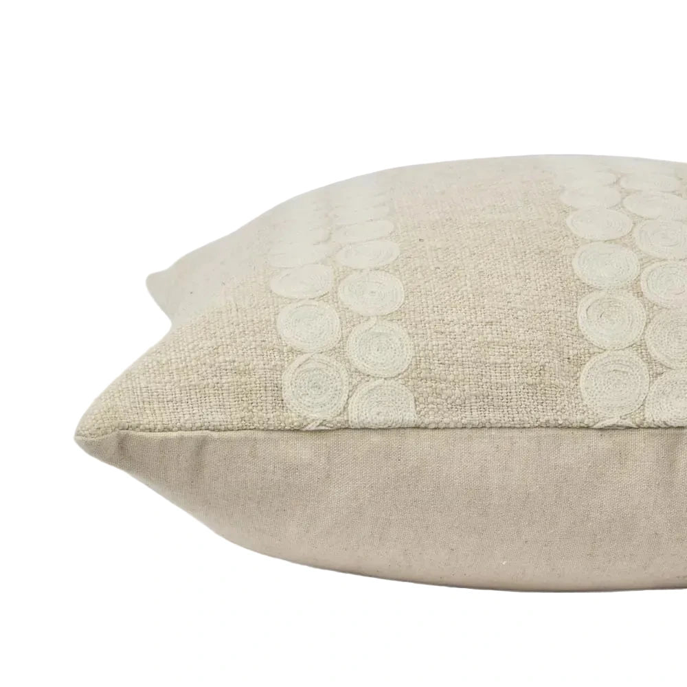 Beige pillow with floral embroidery on a light gray background