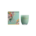Green candle with floral packaging on a white background