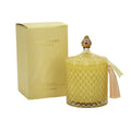 Yellow textured candle with decorative lid and tassel next to its packaging on a white background