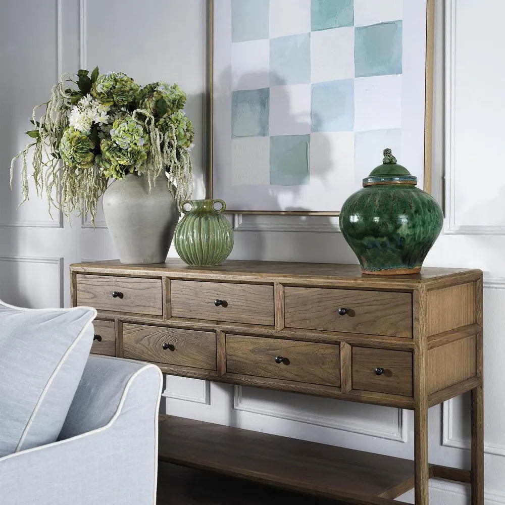 Wooden console table with decorative vases and a flower arrangement in a living room setting.