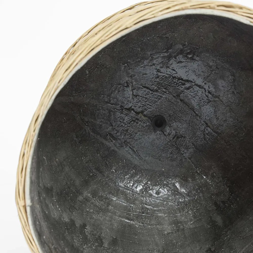 Close-up of a textured black pot with a woven rim on a white background