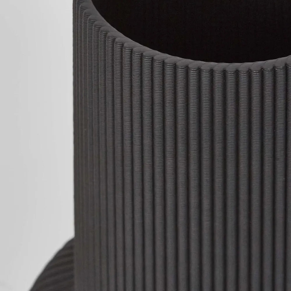 Close-up of a textured black vase on a light gray background