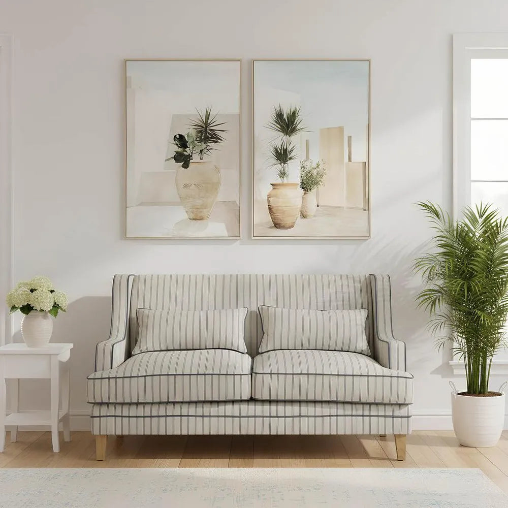Living room with a striped sofa, framed artwork, and decorative plants.